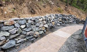 After photo of a sloped yard with a retaining wall. 